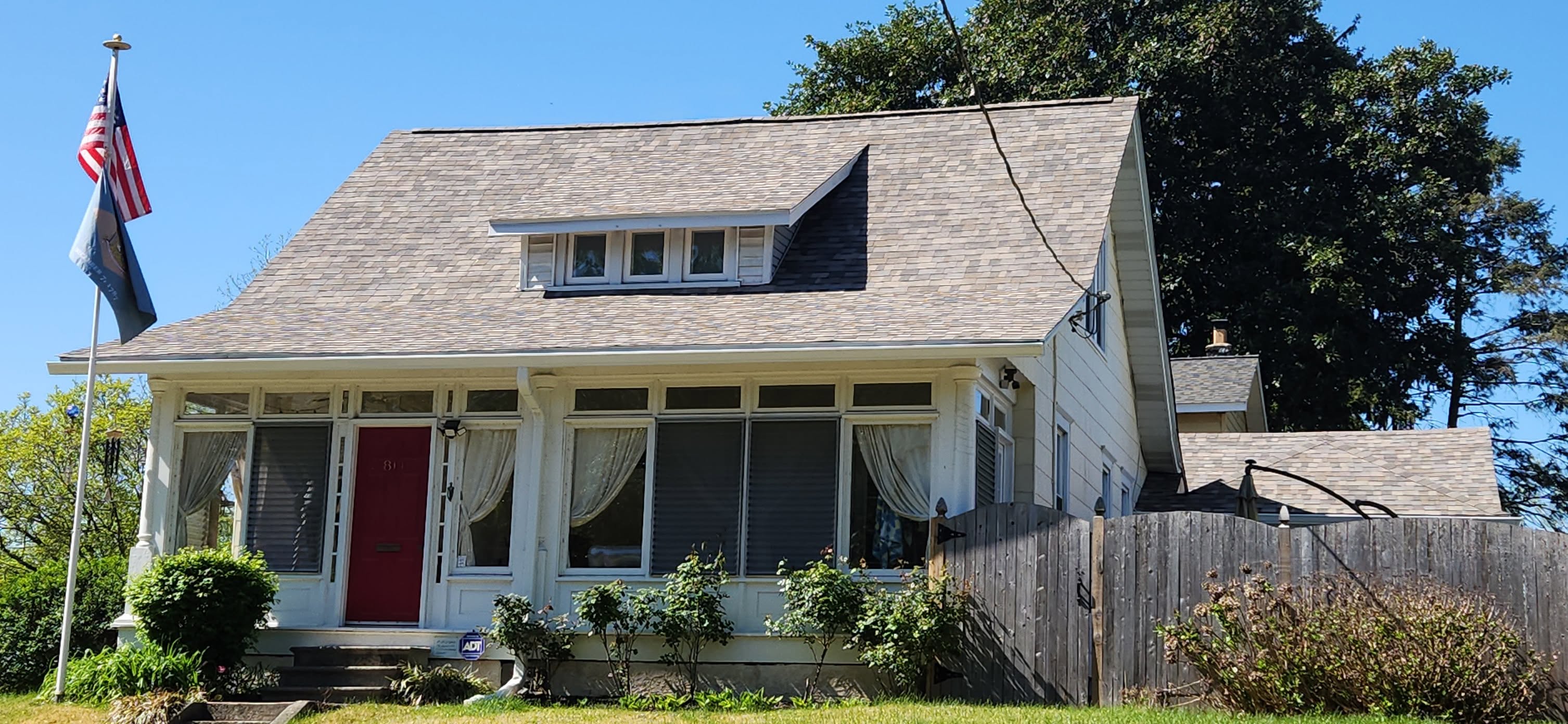 Completed residential roof on a house displaying the American flag